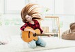 Cute young girl with guitar waving long hair in modern room