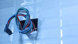 Fototapeta  - Electrical wires in holes in tiled walls. Closeup of a group of colorful wires for installing electronic equipment on a bathroom wall with wires protruding in a house under construction. Select focus