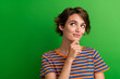 Photo portrait of lovely young lady touch chin look minded empty space dressed stylish striped garment isolated on green color background