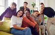 © Studio Romantic - Portrait of a group of happy young diverse friends men and women sitting on sofa in the living room at home looking cheerful at camera enjoying meeting. Friendship, party and home leisure concept.