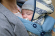 Close up of a baby sleeping in a baby carrier on his mother's chest or cleavage, in an exceptionally intimate closeness