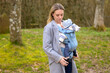 Happy woman looking to her baby while holding and carrying it in a baby carrier