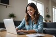 © ThomasLENNE - Smiling young woman using laptop at home