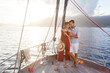 Traveling on yacht by sea at sunset. Happy couple in love drinking wine on sailboat. Travelers relaxing and enjoying summer vacation. Intimate romantic dating, celebration with beautiful view, nature