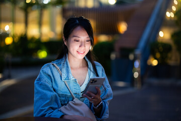 Wall Mural - Woman use mobile phone at outdoor bar in the evening