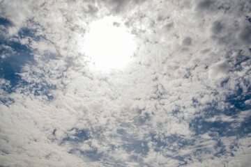 Wall Mural - The sky is cloudy and the sun is shining through the clouds. The sun is creating a bright spot in the sky