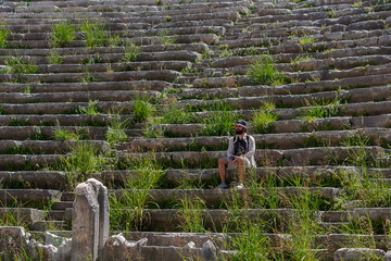 Wall Mural - A male tourist enjoys a walk through the amphitheater among the ruins of the ancient city of Perge, in Turkey. The tourist looks around the ancient city of Perge with fascination