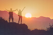 silhouette, young man and woman celebrating victory looking out to the mountain sunrise 


