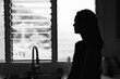 young unrecognizable unhappy woman alone looking out her kitchen window 