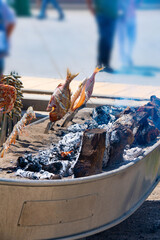 Skewers of octopus, sea bream, shrimp and sardines, grilled over a wood fire in a boat on the sand of the beach. Typical dish from Malaga, Andalusia, Spain.