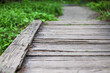 An old cracked and damaged wooden bridge in a park. Photo in perspective with selective focus