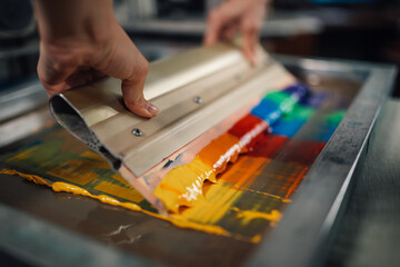 Wall Mural - Close up of print shop worker's hands using squeegee for screen printing