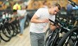 Young man buyer chooses bicycle in sports store