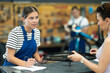 Young female worker signs agreement with female client at bicycle repair service