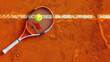 tennis ball on orange clay court with racquet, with copy space for text