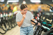 Young woman buyer chooses bicycle in sports store