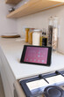A tablet displaying smart home interface rests on a kitchen counter at home