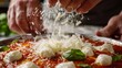A closeup of hands sprinkling freshly grated mozzarella cheese on top of the sauce the cheese beginning to melt in the heat.
