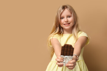 Wall Mural - Happy little girl with sweet chocolate bar on brown background