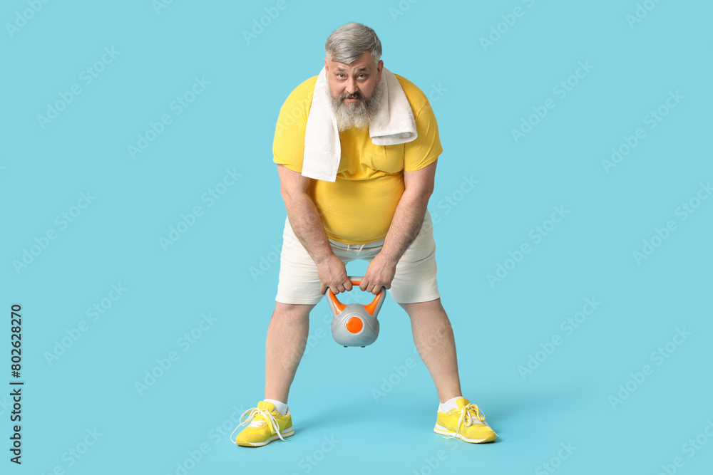 Overweight mature man with kettlebell on blue background. Weight loss concept