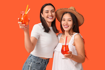 Sticker - Beautiful young women with glasses of cocktail on orange background. Summer party