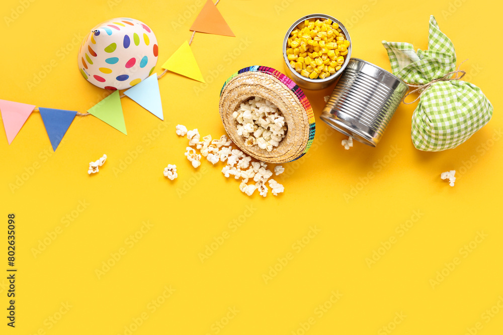 Composition with tasty popcorn, corn, bundle bag and decor for Festa Junina celebration on yellow background