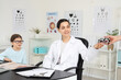 © Pixel-Shot - Female ophthalmologist with little girl taking trial frame in clinic