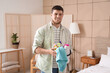 Young bearded man with bucket of cleaning supplies in bedroom