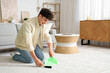 © Pixel-Shot - Young man sweeping carpet at home