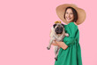Young woman with cute pug dog on pink background