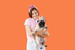 Young woman and cute pug dog with princess headbands on orange background