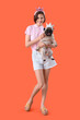 Young woman and cute pug dog with princess headbands on orange background