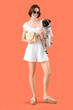 Young woman with cute pug dog and handbag on orange background