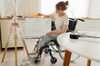 Young woman in wheelchair wrapping lamp during repair at home