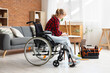 Young woman in wheelchair repairing table at home