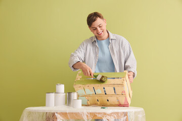 Canvas Print - Young man with brush painting wooden box near green wall