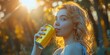 A young woman drinking from yellow drink can with a blurry nature backdrop in a summer day with a big space for text or product background, Generative AI.