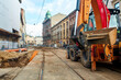 Sewerage and water supply repairs in the old streets of Europe. An excavator stands on a dug-up road to replace old pipes with new ones.