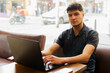 © fx-visual - A young man sits at a table with a laptop in front of him