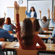 © jiraporn - A female student raises her hand to answer a question from the teacher in a classroom.