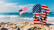 © woret - Patriotic flipflops on the beach with American flag in background
