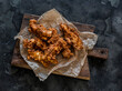 Deep-fried chicken breast pieces in batter - delicious snack, tapas on a cutting board on a dark background, top view