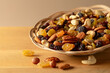 Mix of dried nuts and raisins on a wooden background.