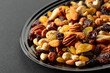 Mix of dried nuts and raisins on a black background.