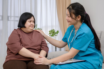 Wall Mural - Asian girl with a disability Down syndrome child fat Smiling and cute talking to an Asian female nurse or therapist about obesity in the living room at home.