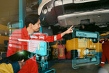 Fototapeta  - Car mechanic inspects car using technology and computer show resault at virtual screen.