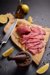 Wall Mural - Woman cut tuna steak into slices on a wooden cutting board at domestic kitchen cooking tuna carpaccio