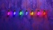   A multicolored string of light bulbs dangles from a purple-painted wire on a deep purple backdrop