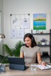 © Wasana - A woman wearing headphones is sitting at a desk with a laptop