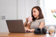 © Wasana - A woman is sitting at a desk with a laptop and a pink mug of coffee